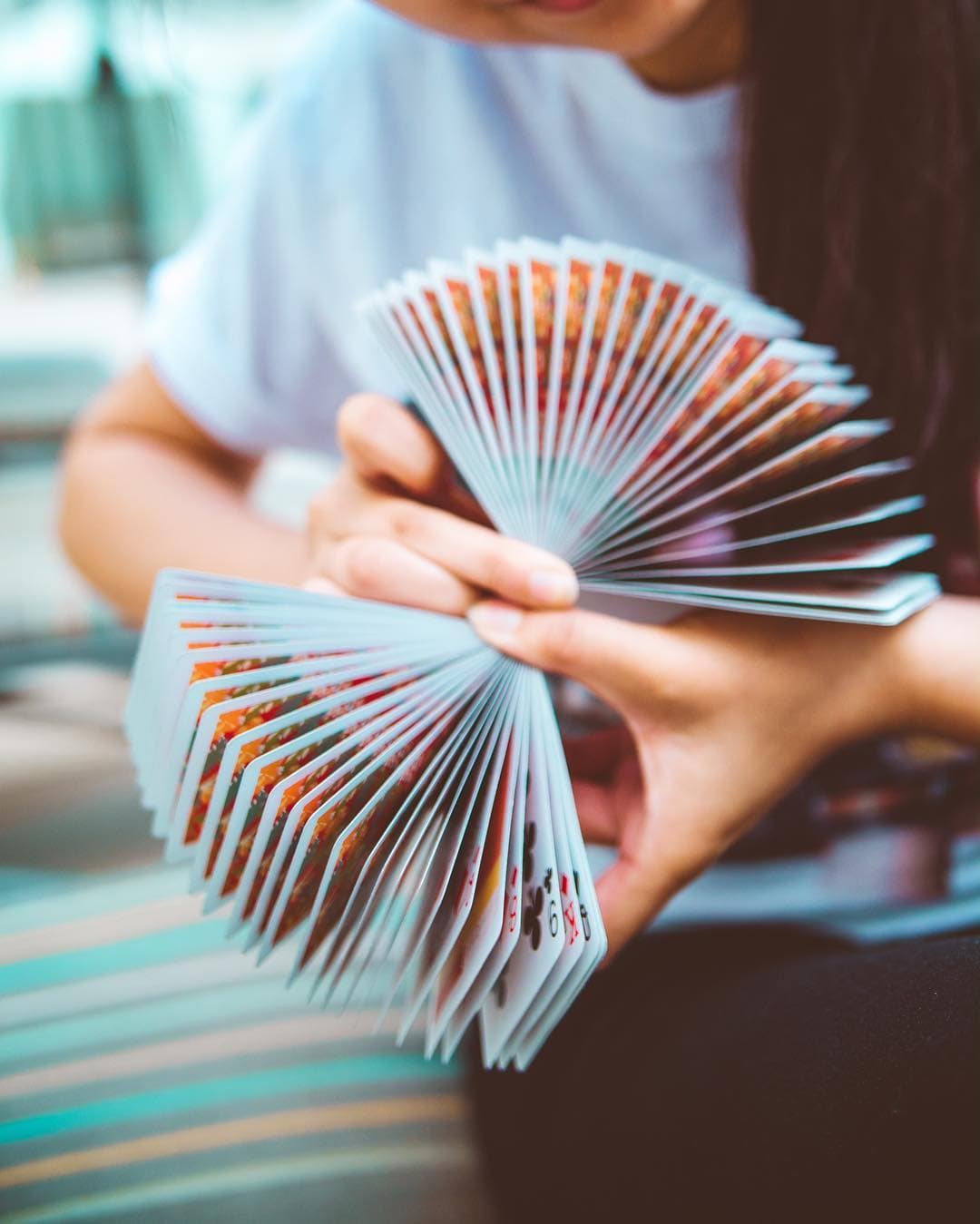 Two hands holding a wide double fan of cards, the faces stepped into a spiral.
