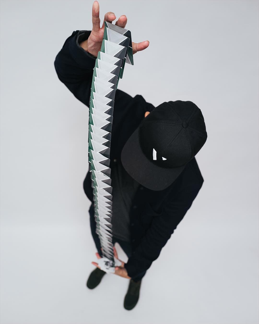 Seen from directly above, a cardist in black with a long ribbon spread of cards running the full length of his body.